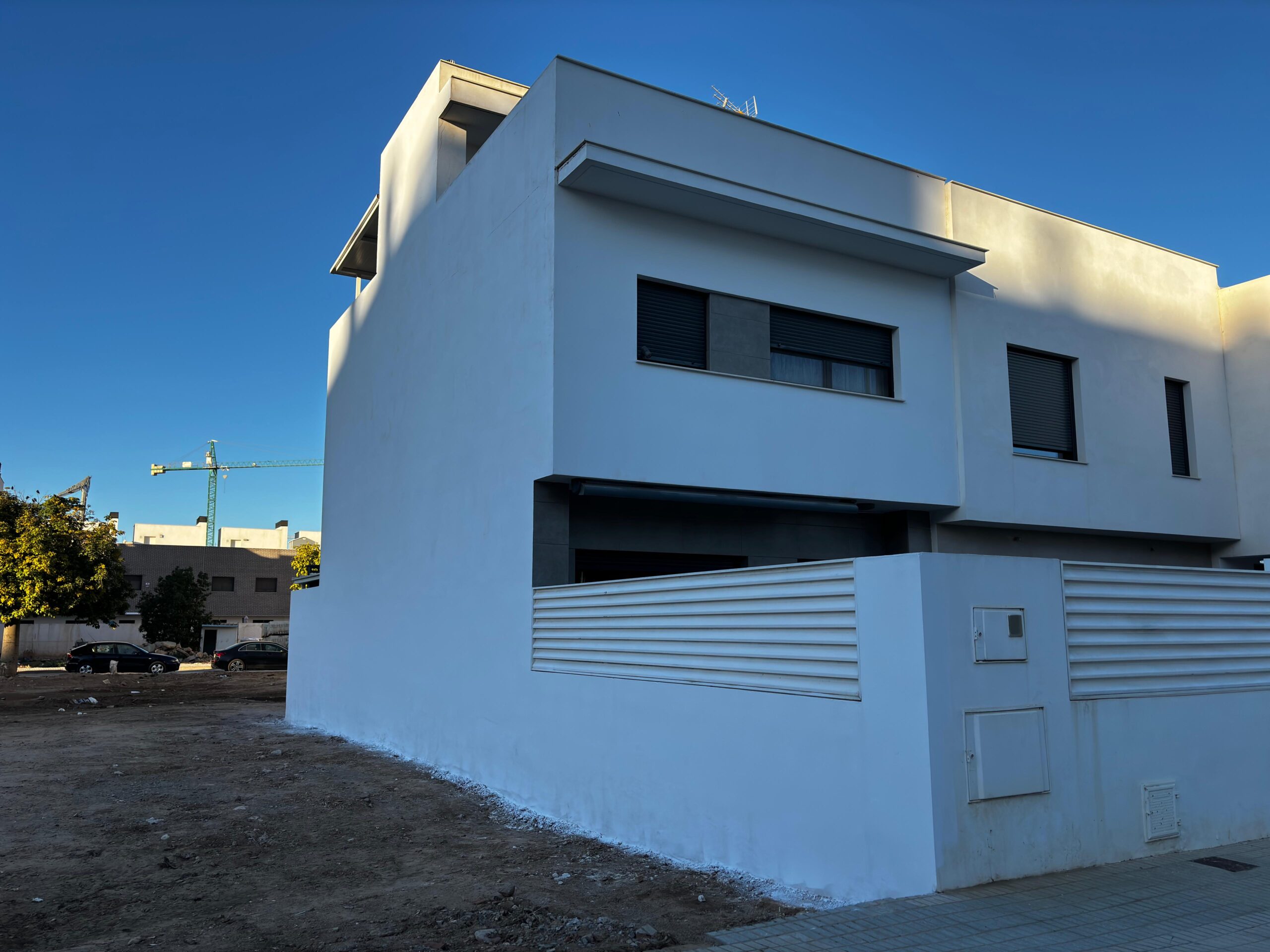 Fachada rehabilitada en Paiporta tras la DANA con vallado y puerta pintados