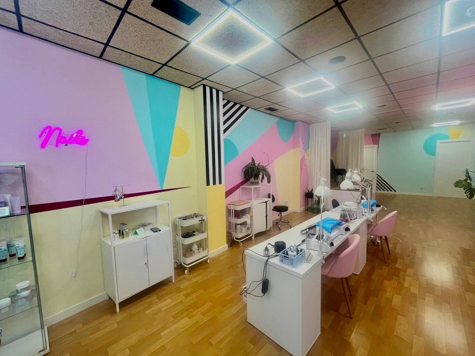 Zona de pedicura y neón decorativo sobre pared rosa en el local de Beatriz Ruiz