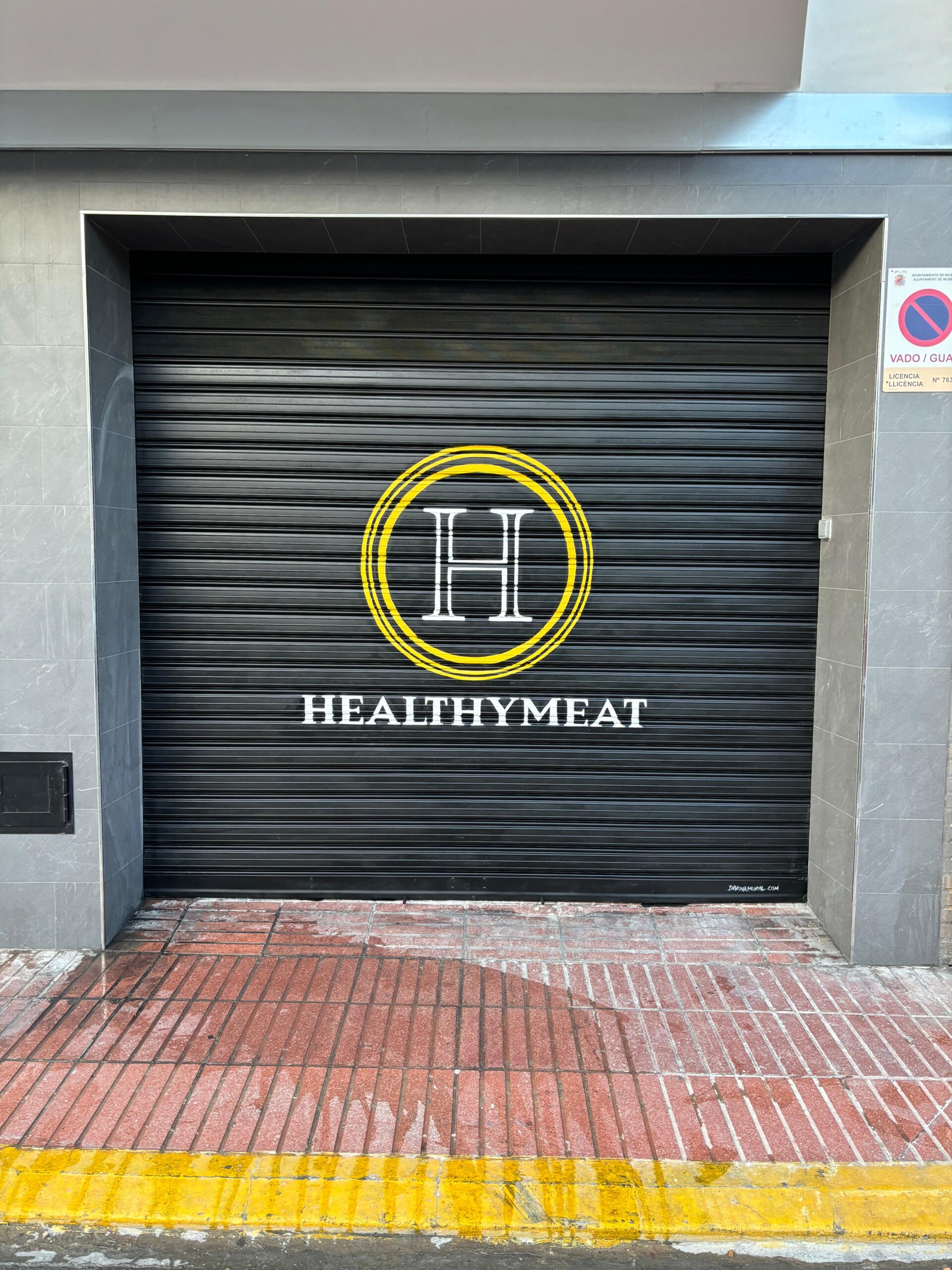 Detalle final del logotipo HealthyMeat rotulado en persiana negra