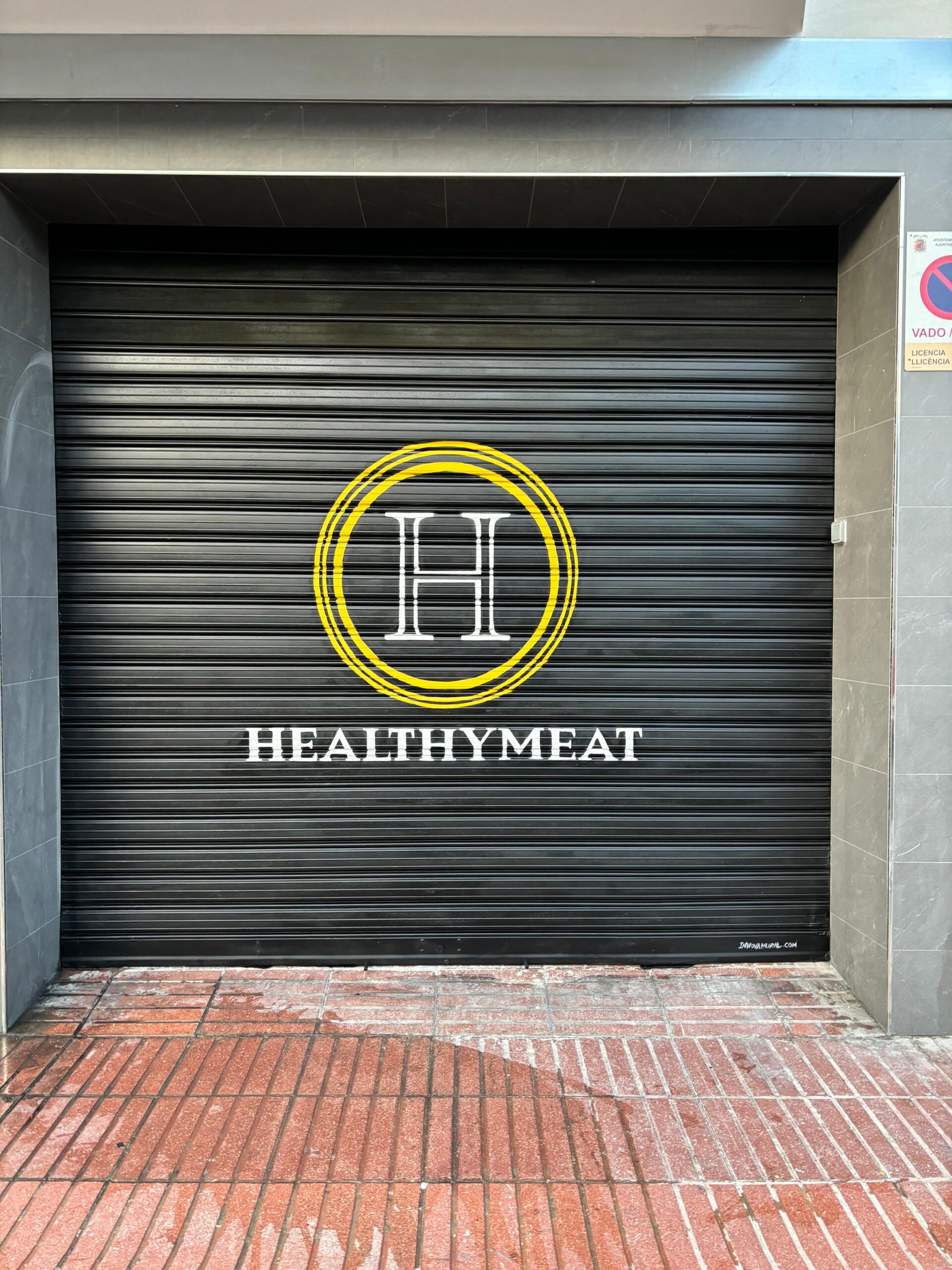 Logotipo en amarillo y blanco de HealthyMeat acabado sobre la persiana metálica